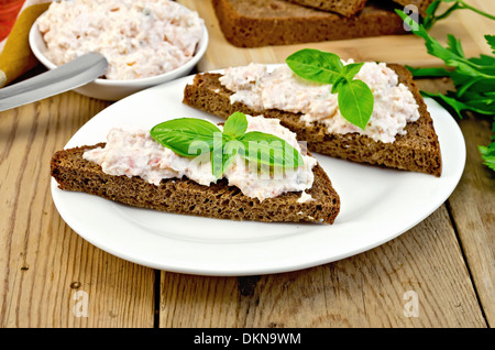 Sandwichs sur deux morceaux de pain de seigle avec de la crème de saumon et mayonnaise, basilic, couteau, serviette sur les planches en bois Banque D'Images