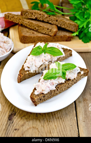 Sandwichs sur deux morceaux de pain de seigle avec de la crème de saumon et mayonnaise, basilic, persil, une serviette sur les planches de bois Banque D'Images