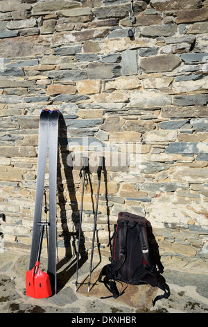 Paire de ski tour avec sac à dos et de pelle à avalanche rescue sur vieux mur de pierre du chalet de montagne dans les Alpes italiennes Banque D'Images