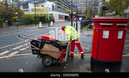 Les bas salaires des travailleurs conseil street cleaner avec un balai et dustcart travaillant à côté d'une boîte postale rouge dans la région de Golden Lane Londres EC2Y England UK KATHY DEWITT Banque D'Images