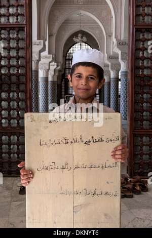 La Libye, Zliten. Jeune garçon montrant sa prière sur lequel il a écrit des versets du Coran. Banque D'Images