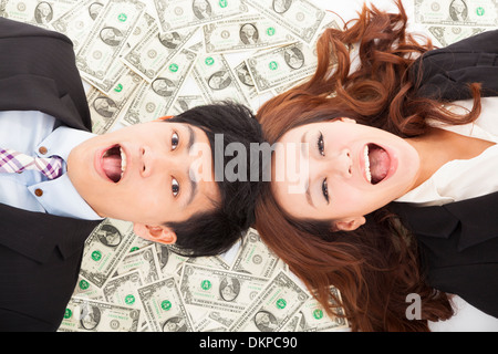 Surpris businessman and woman lying on l'argent Banque D'Images