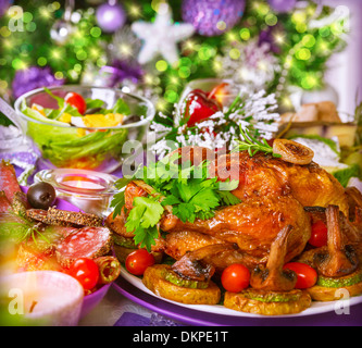 Table de Noël traditionnel Arbre de Noël décoré sur le fond, de délicieux légumes poulet rôti au four avec Banque D'Images