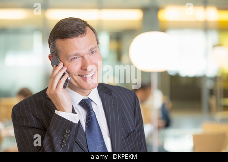 Businessman talking on cell phone in office Banque D'Images