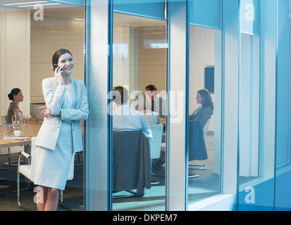 Businesswoman talking on cell phone in meeting Banque D'Images