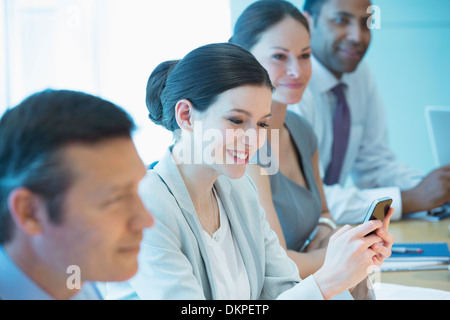 Businesswoman using cell phone in meeting Banque D'Images