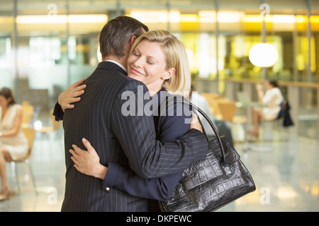 Les gens d'affaires hugging in office Banque D'Images