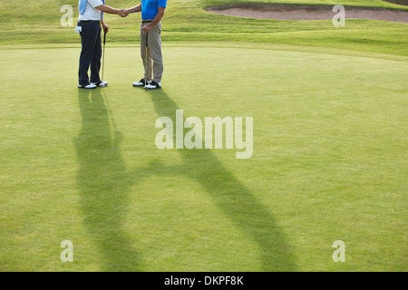 Senior men shaking hands on golf course Banque D'Images