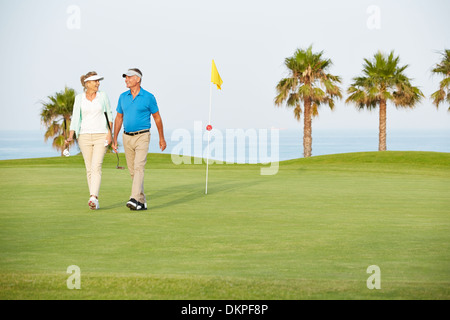 Senior couple walking on golf course Banque D'Images