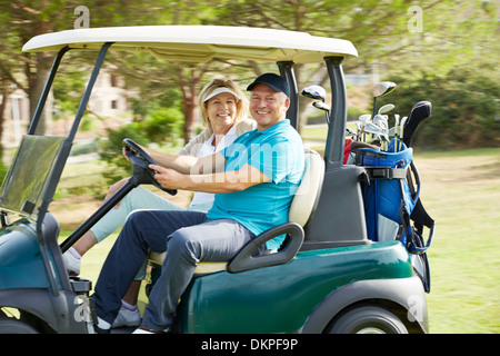 Senior couple roulant chariot de golf on course Banque D'Images