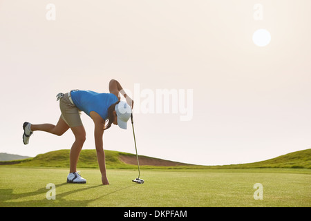 Woman Reaching for ball dans le trou on golf course Banque D'Images