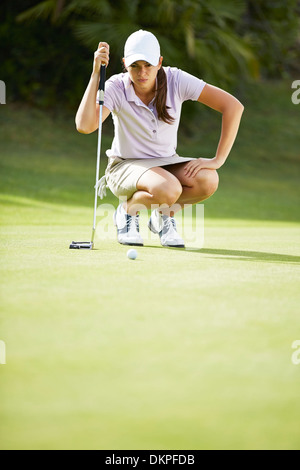 Woman preparing to putt on golf course Banque D'Images