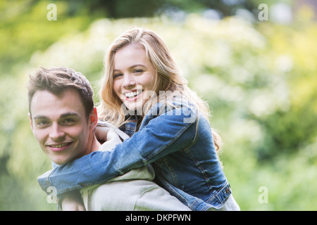 Man carrying girlfriend piggyback outdoors Banque D'Images