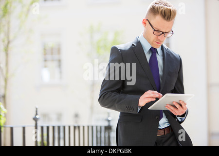Businessman using digital tablet on city street Banque D'Images