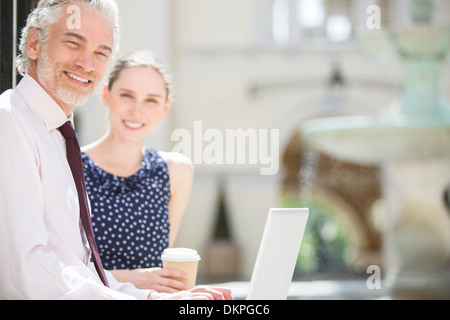 Business people using laptop outdoors Banque D'Images