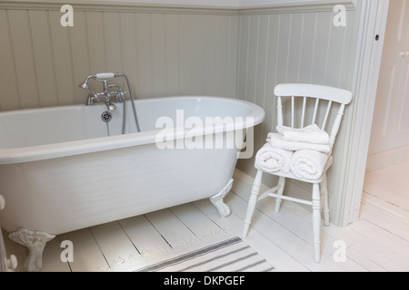 Une baignoire et une chaise dans une salle de bains privative ornée Banque D'Images