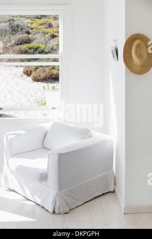 Fauteuil à côté de fenêtre donnant sur plage Banque D'Images