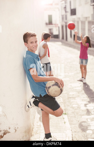 Boy holding soccer ball in alley Banque D'Images