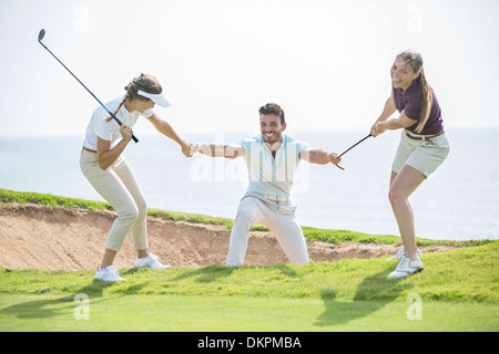 Les femmes tirant sur l'homme de fosse de sable on golf course Banque D'Images