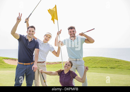 Amis enthousiastes agitant on golf course Banque D'Images