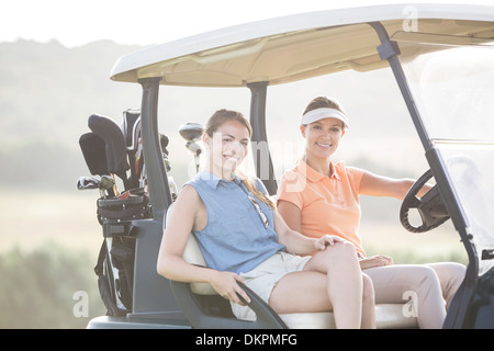 Les femmes au volant sur chariot de golf course Banque D'Images