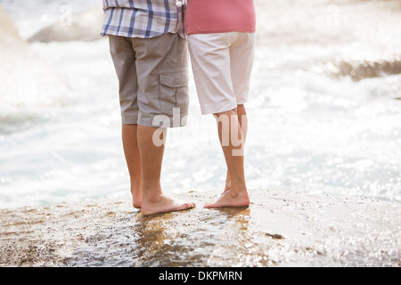 Senior couple standing on rock at beach Banque D'Images