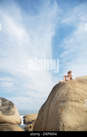 Couple sitting on rock formation on beach Banque D'Images