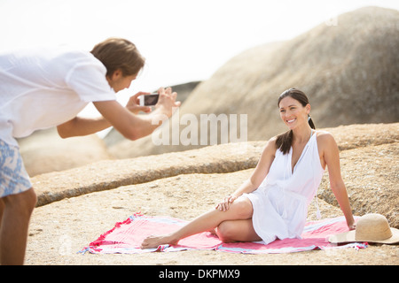 Man taking picture of girlfriend on beach Banque D'Images