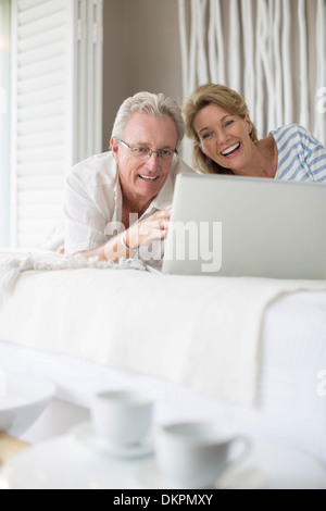 Vieux couple using laptop on bed Banque D'Images