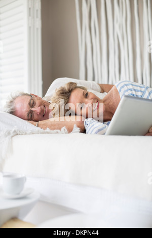 Vieux couple using digital tablet on bed Banque D'Images