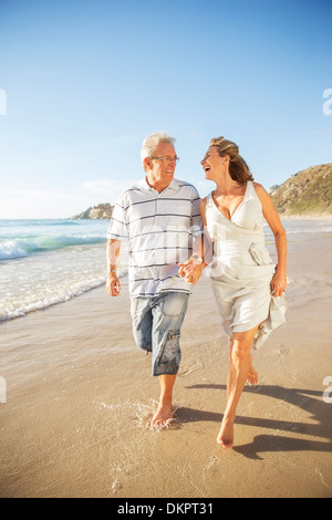 Senior couple walking in surf on beach Banque D'Images