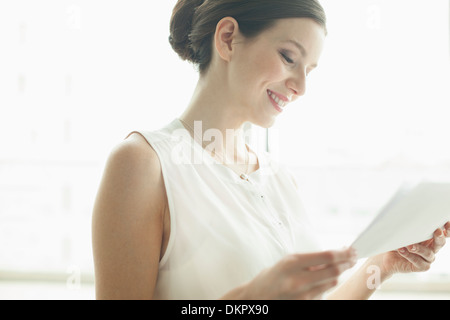 Businesswoman reading papers in office Banque D'Images