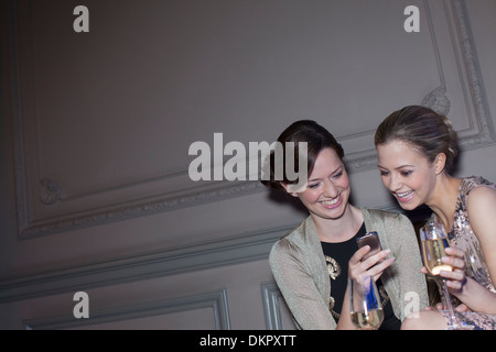 Les femmes bien habillées de boire du champagne et à at cell phone Banque D'Images