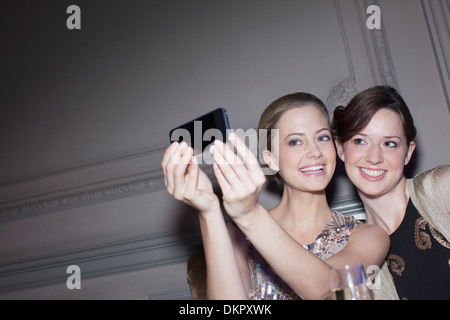 Smiling women taking self-portrait with camera phone Banque D'Images