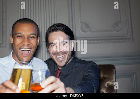 Close up portrait of smiling men toasting beer and cocktail Banque D'Images