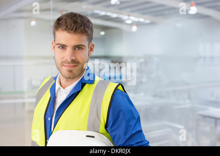 Worker smiling par fenêtre en usine Banque D'Images