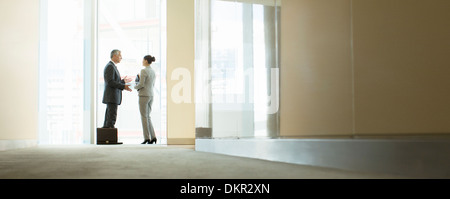 Business people talking at office window Banque D'Images