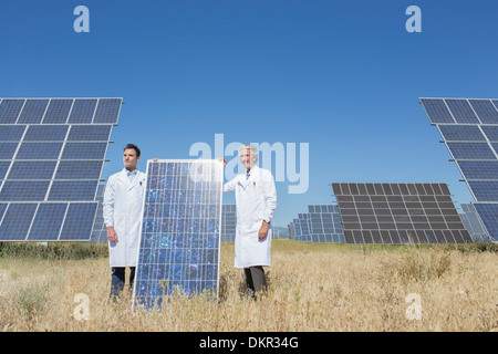 Les scientifiques holding solar panel in rural landscape Banque D'Images