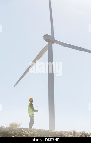 Businessman examining wind turbine in rural landscape Banque D'Images