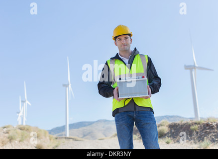 Worker standing by wind turbines in rural landscape Banque D'Images