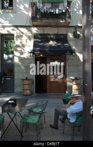 Espagne, Catalogne, Barcelone, Rambla del Raval, Man wearing hat assis à table à l'extérieur du restaurant catalan Suculent. Banque D'Images