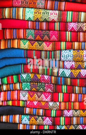 Fait à la main d'Amérique du Sud en tissu coloré avec les schémas traditionnels et design. Tissu en une pile dans un marché de Lima, Pérou. Banque D'Images