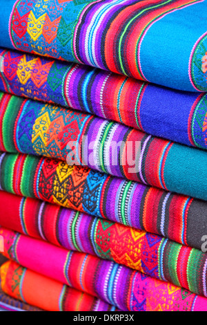 Fait à la main d'Amérique du Sud en tissu coloré avec les schémas traditionnels et design. Tissu en une pile dans un marché de Lima, Pérou. Banque D'Images