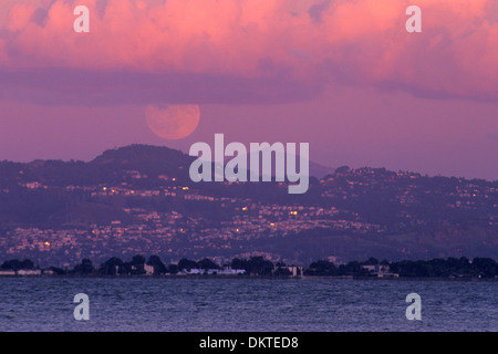 La pleine lune au coucher du soleil sur l'Oakland Hills et Mount Diablo, vu de Rincon, San Francisco, Californie Banque D'Images