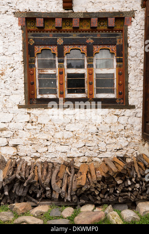 Le Bhoutan, la vallée de Bumthang, Gaytsa Village, bois de chauffage en dessous de la fenêtre de la décoration traditionnelle Banque D'Images