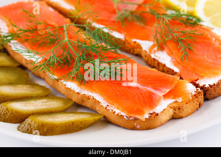 Sandwiches au saumon avec cornichon et citron sur la plaque libre de droit. Banque D'Images