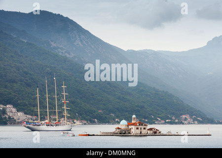 Baie de Kotor. Petite île Notre Dame des roches et grand voilier Banque D'Images