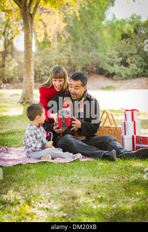 Young Mixed Race Family Enjoying Cadeaux de Noël dans le parc ensemble. Banque D'Images