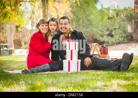 Young Mixed Race Family Enjoying Cadeaux de Noël dans le parc ensemble. Banque D'Images