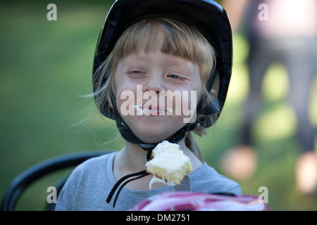 Polish girl vêtue de son nouveau casque de vélo profitant de gâteau d'anniversaire. Zawady Centre de la Pologne Banque D'Images